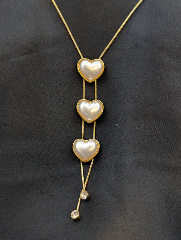 Gold-plated stainless steel lariat necklace featuring three cascading heart charms with pearl inlays and crystal drop accents.