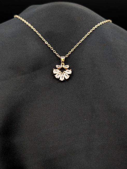Gold-plated stainless steel necklace with a fan-shaped sunburst pendant featuring pear-cut crystals on a black background.