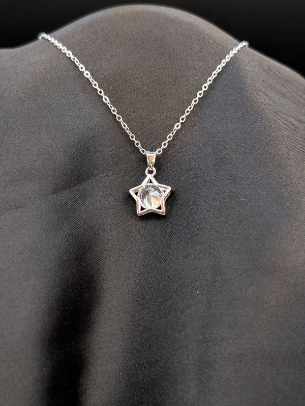 Silver-toned stainless steel star pendant necklace with a large round crystal center on a black background.