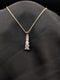 Gold-plated stainless steel necklace with a vertical tiered drop pendant featuring five graduated square-cut crystals on a black background.