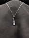 Silver-toned stainless steel necklace with a vertical tiered drop pendant featuring five graduated square-cut crystals on a black background.