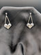 Silver-toned chandelier earrings featuring a cascading crystal design and a pave-encrusted heart pendant on a dark grey background.