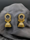 Antique gold-toned Jhumka earrings featuring a crystal-encrusted circular stud and detailed filigree bell pendants with gold bead accents on a dark background.