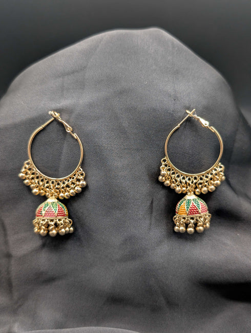 Gold-toned hoop earrings featuring a central Jhumka bell with multi-color enamel work and a beaded fringe on a dark fabric background.