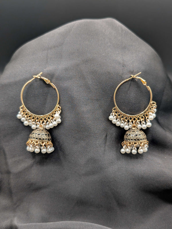 Gold-toned Jhumka hoop earrings featuring a filigree bell pendant and a fringe of white pearls on a dark grey background.