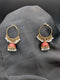 Gold-toned Jhumka hoop earrings with vibrant ruby red enamel bells and white pearl fringe against a dark background.
