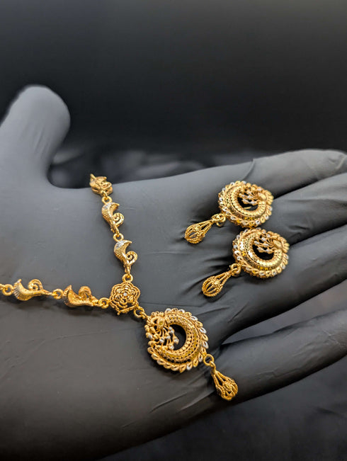 Handheld 24k gold plated necklace set featuring a peacock and crescent moon pendant with silver accents and matching earrings.