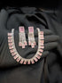 Close-up of a blush pink 1 Karat Zircon necklace and earring set for romantic styling.