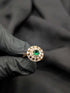 Vintage-inspired emerald green cocktail ring with tapered baguette crystal halo held in a gloved hand.