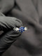 Silver ring featuring a blue sapphire-colored flower cluster center and a unique articulated link band held against a black background.