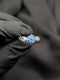 Close-up of a silver ring with a light blue flower-shaped crystal cluster and a unique geometric link-style band.