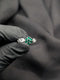 Close-up of a vibrant green emerald-tone flower cluster ring with a polished silver geometric link band.