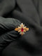 Detailed view of a gold sunburst ring with a red marquise ruby center and clear crystal star accents.