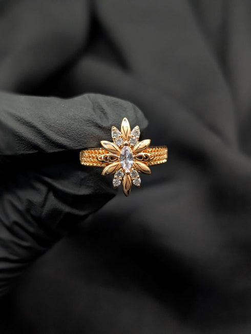 Detailed view of a gold starburst statement ring with a clear marquise crystal center and a textured gold band.