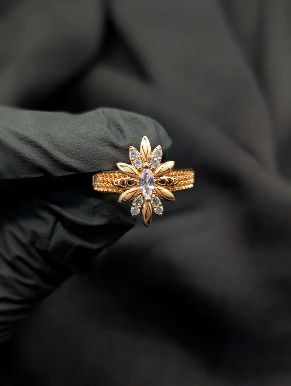 Detailed view of a gold starburst statement ring with a clear marquise crystal center and a textured gold band.