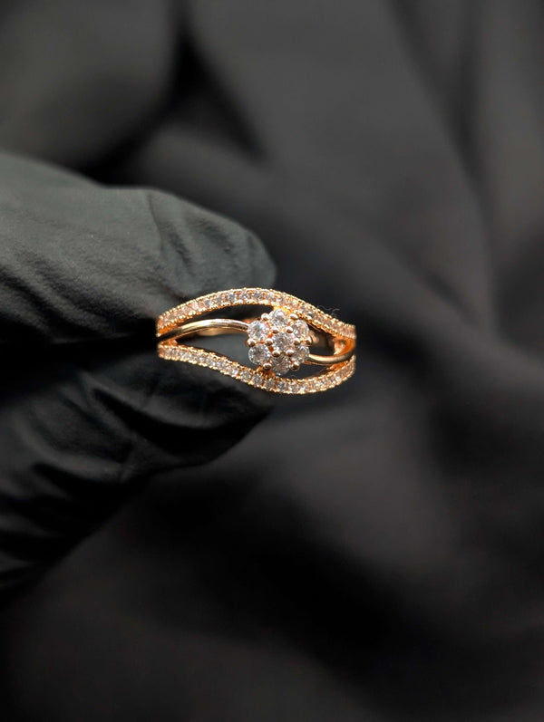 Rose gold bypass ring featuring a central clear floral cluster and two curving rows of pavé-set crystals held in a black gloved hand.