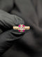 Gold-tone statement ring with a clear rectangular baguette center stone accented by four round ruby-red gems.