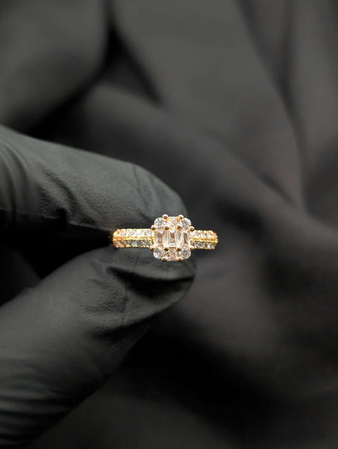 Gold-tone statement ring with an all-clear rectangular baguette center stone accented by four matching round brilliant crystals.