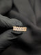 Close-up of a gold-tone eternity band featuring a continuous row of shimmering marquise-cut clear crystals held in a black gloved hand.