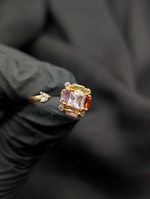Gold open-ended statement ring featuring a cluster of pastel-colored square and baguette crystals with a clear teardrop accent stone.