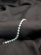 Polished silver-tone tennis bracelet with alternating mint green and clear white princess-cut crystals on a dark textured background.