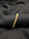 A polished gold-tone bangle with an intricate woven mesh texture laid across a dark, draped fabric.