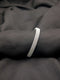 A polished silver-tone bangle with an intricate woven mesh texture displayed on a dark, flowing fabric background.