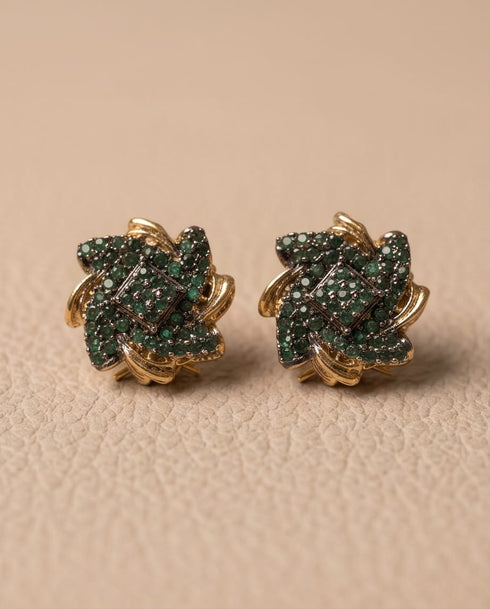 Gold plated emerald stone stud earrings pair on beige leather background