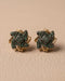 Gold plated emerald stone stud earrings pair on beige leather background
