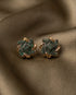 22K gold plated emerald green stone floral stud earrings on brown fabric