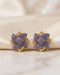 22K gold plated purple stone floral stud earrings on beige fabric