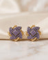 22K gold plated purple stone floral stud earrings on beige fabric