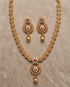 South Indian gold polish necklace and earring set flatlay on beige fabric