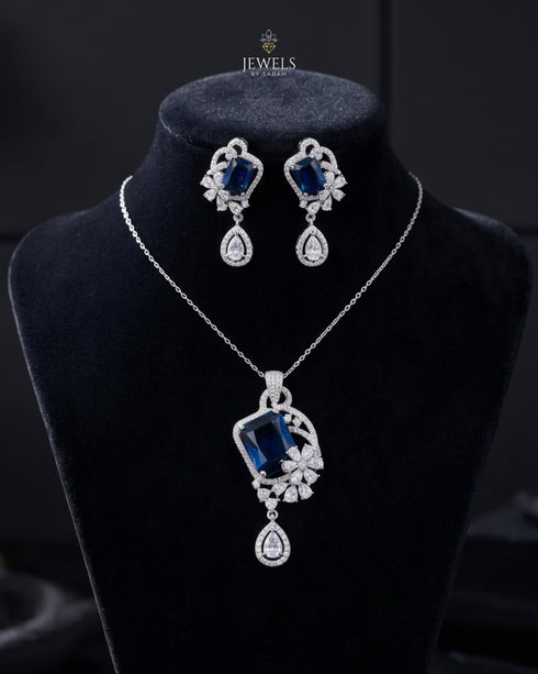 Jewelry set with necklace and earrings featuring blue gemstones on a black background.