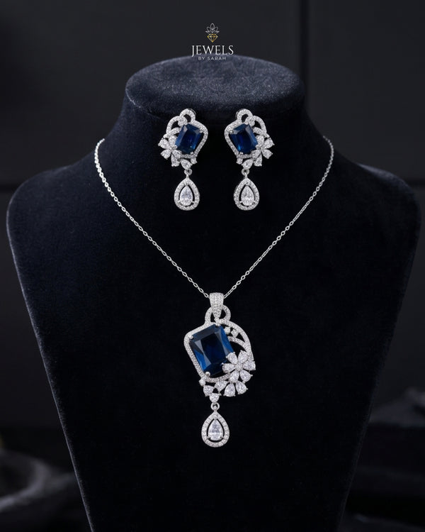 Jewelry set with necklace and earrings featuring blue gemstones on a black background.