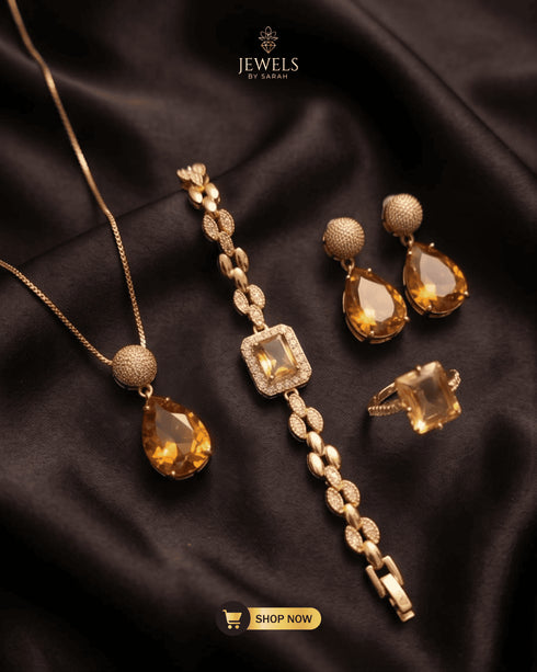 Close up shot of gold finish champagne zircon necklace earrings ring and bracelet on black satin fabric